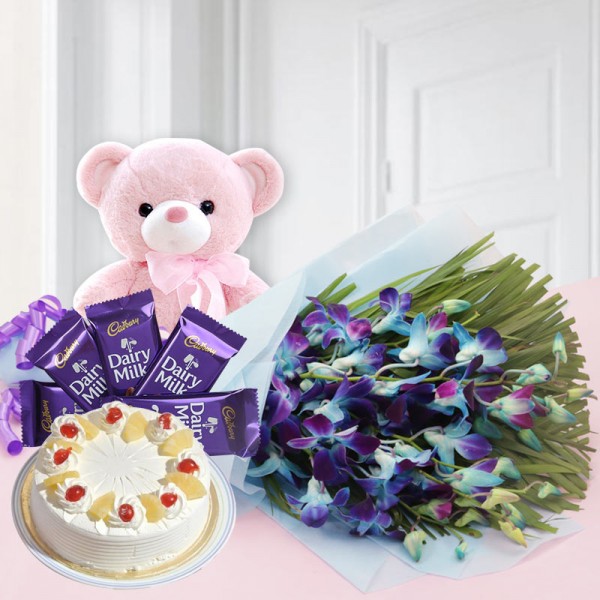  6 Blue Orchids in Blue Paper packing with Half Kg Pineapple Cake, 5 Cadbury's DairyMilk (13.2 gms each) and 1 Teddy Bear (6 inches)